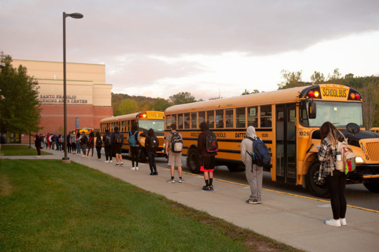 Students exit school bus and await temperature check