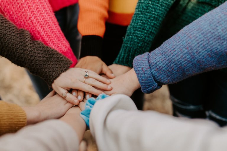 Colorful photo of friends hands piled together; Photo by Hannah Busing on Unsplash.