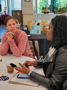 A Black woman talking in a small group session to a white woman, listening intently