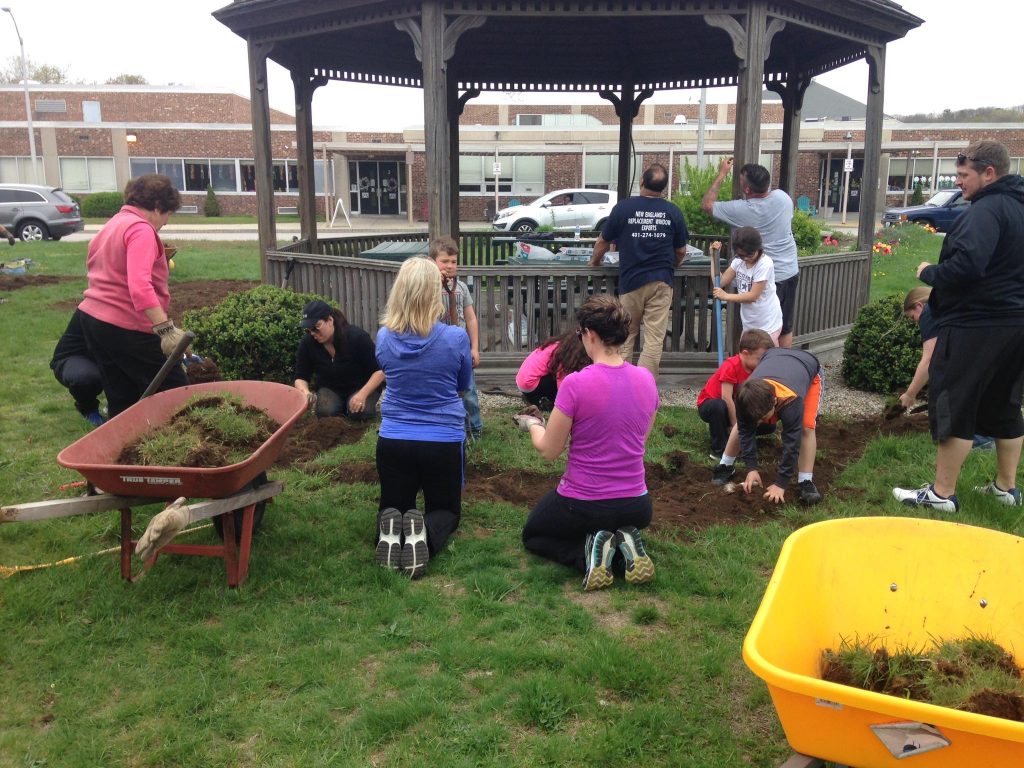 People of different ages planting trees around a gazebo