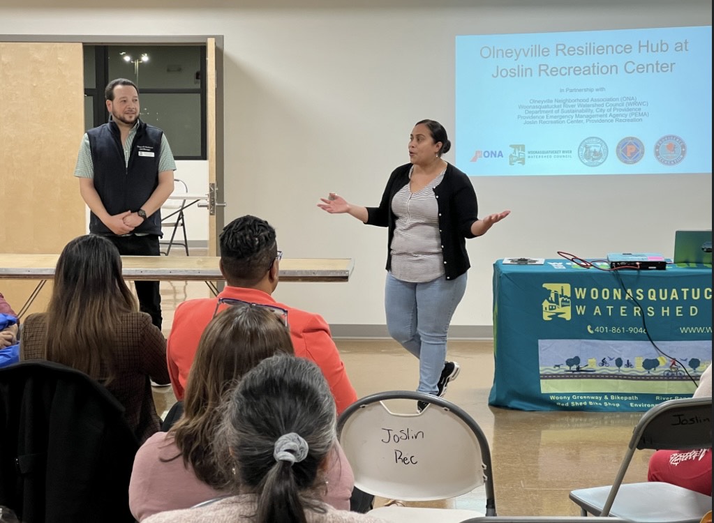 Two people standing in front of a room of people, presenting about a topic